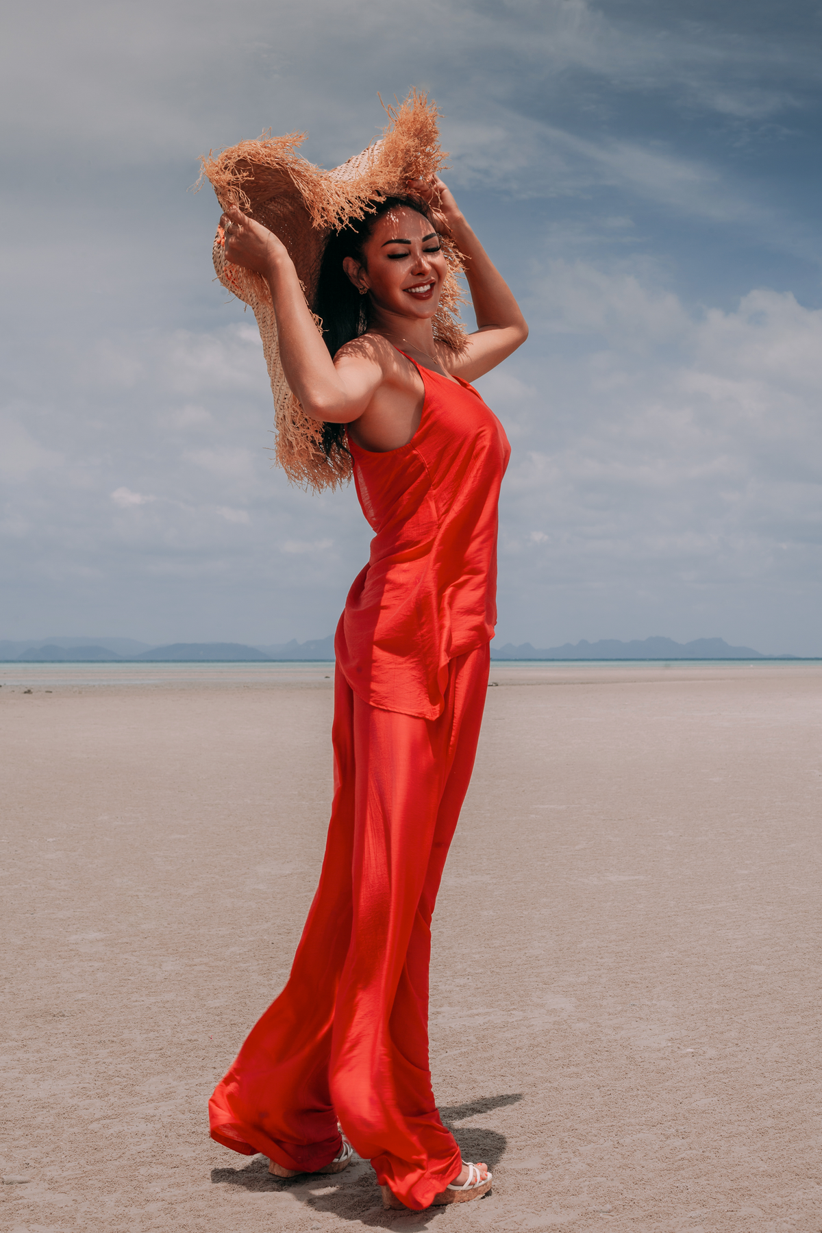 Carmine deep red resort set by INNEVIA with flowing V-neck top and matching wide-leg trousers, full-length look by the sea