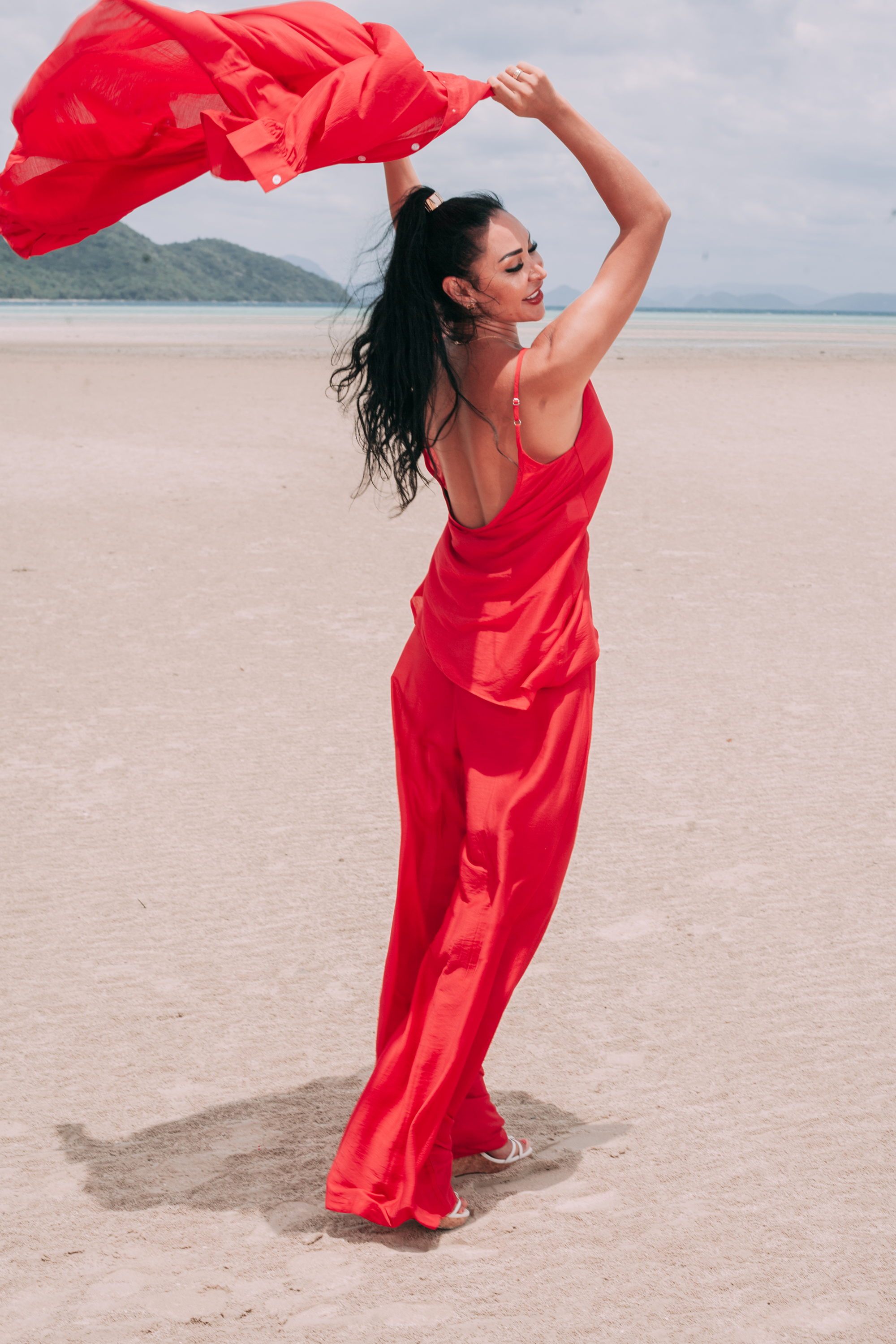 Carmine red resort wear set with flowing wide-leg trousers and lightweight shirt styled on the beach