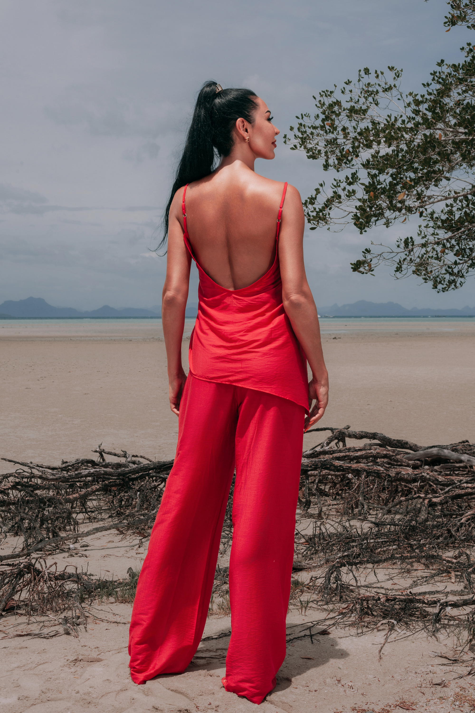 Full back view of Carmine Fluid Pants by INNEVIA styled with the matching Carmine Top, showing the flowing wide-leg silhouette and open-back resort look in deep red