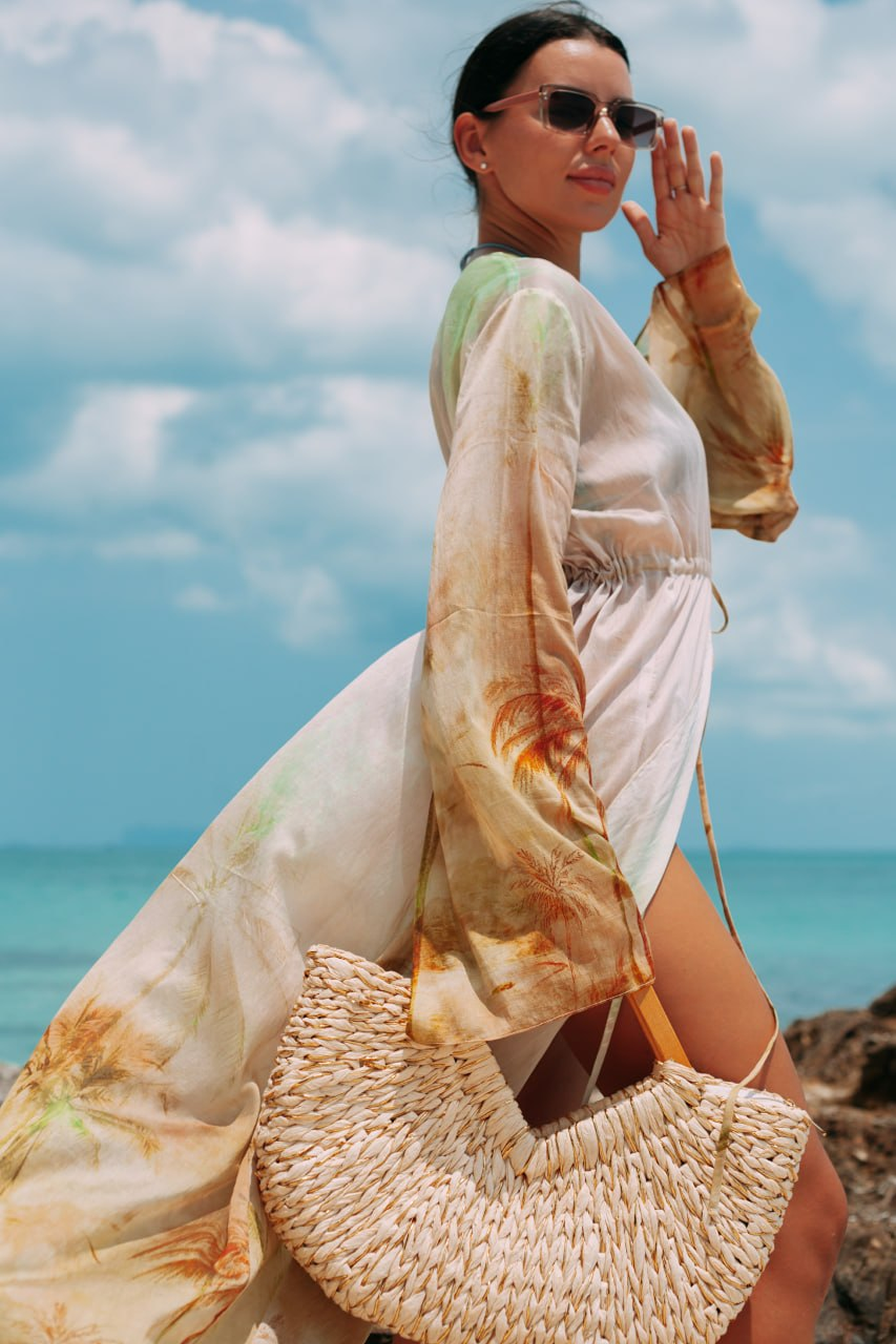 Selara Maxi Tunic in tropical print styled on the beach with a woven straw bag