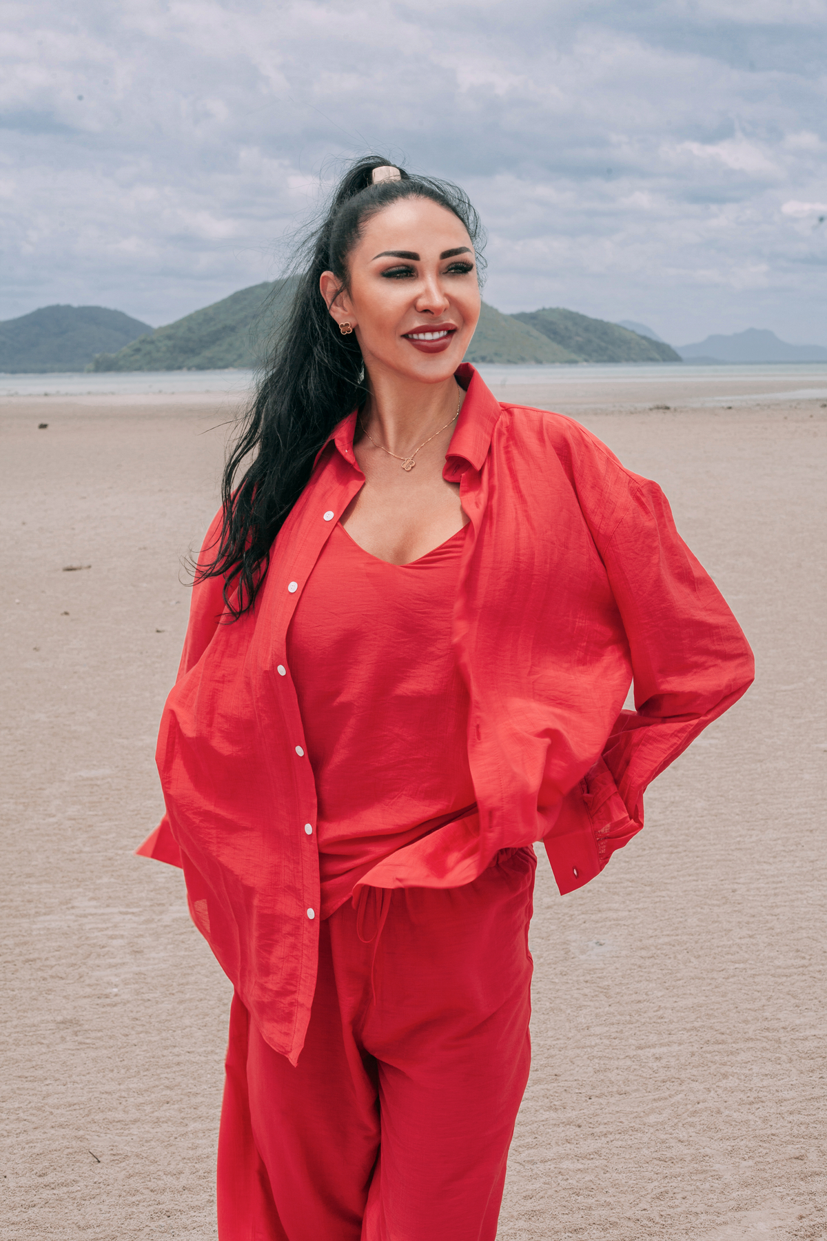 Carmine Relaxed Shirt by INNEVIA styled with the matching Carmine Camisole Top and Fluid Wide-Leg Pants in a deep red resort look on the beach