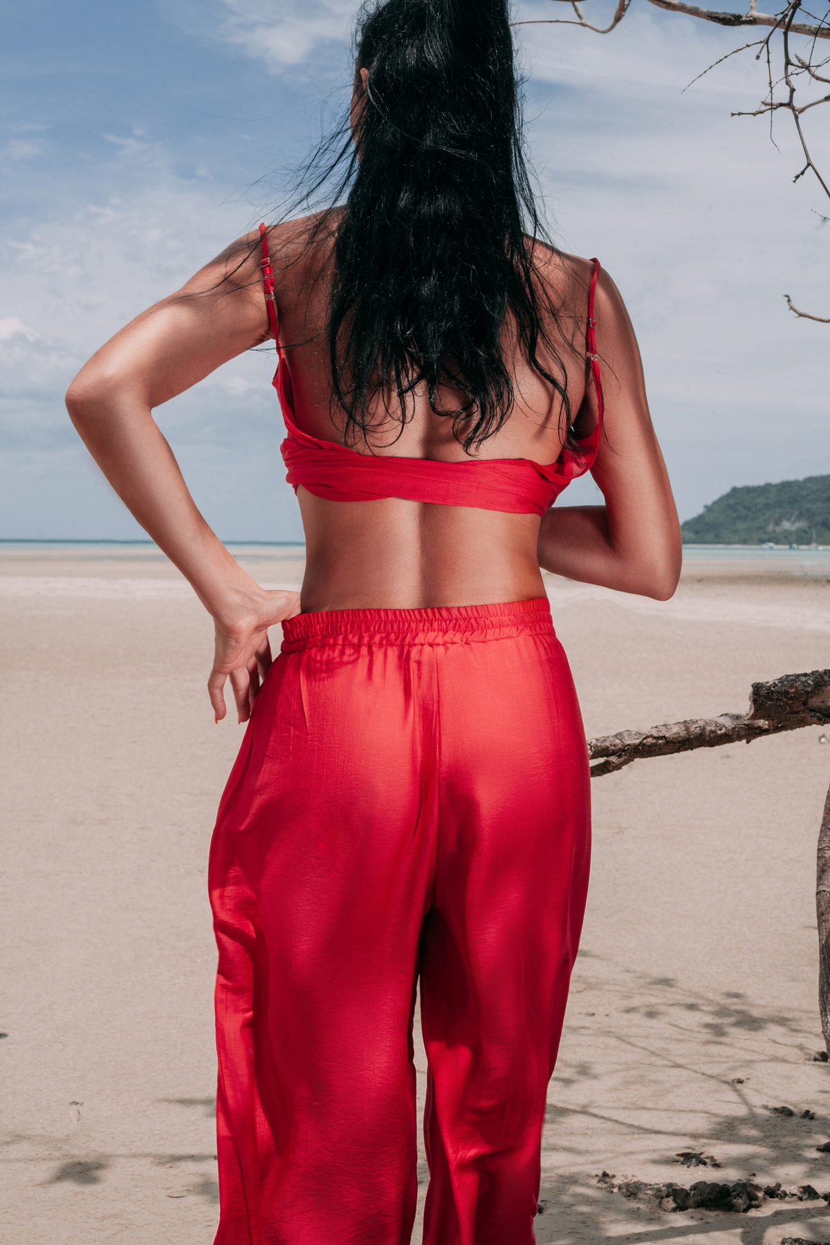 Full back view of Carmine Fluid Pants by INNEVIA, showing the relaxed fit and fluid wide-leg cut of the deep red resort trousers