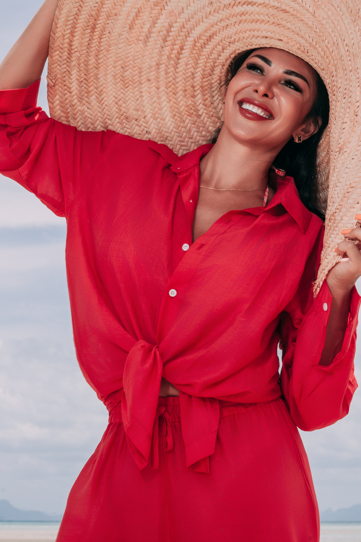 Carmine Relaxed Shirt by INNEVIA styled with matching deep red pants and a wide-brim straw hat for an elegant resort look